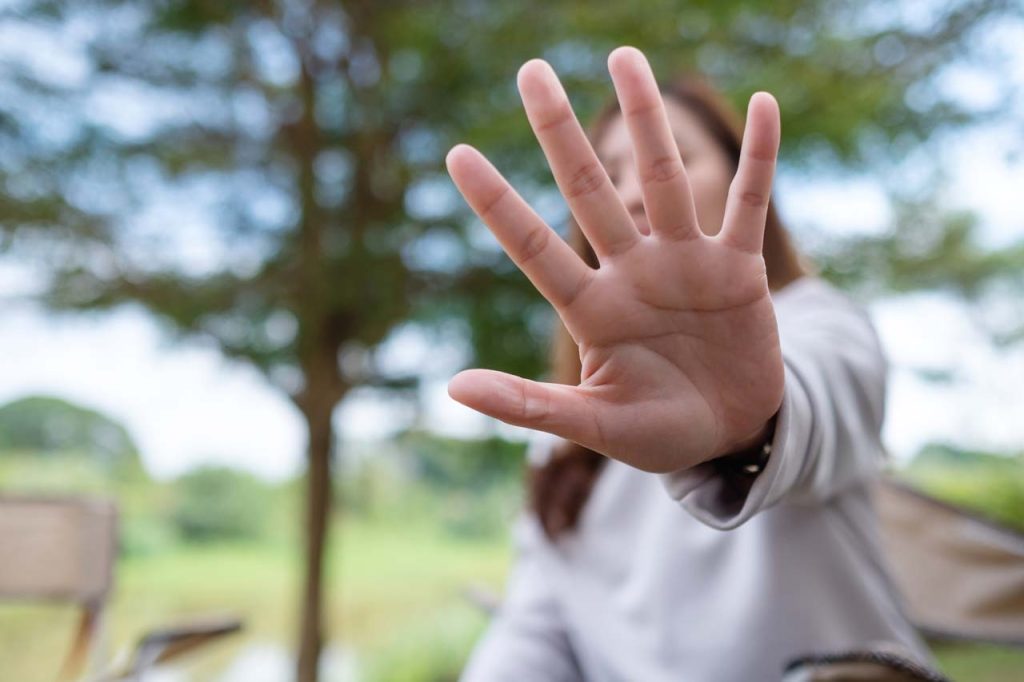 woman holding hand in front of camera, blocking face