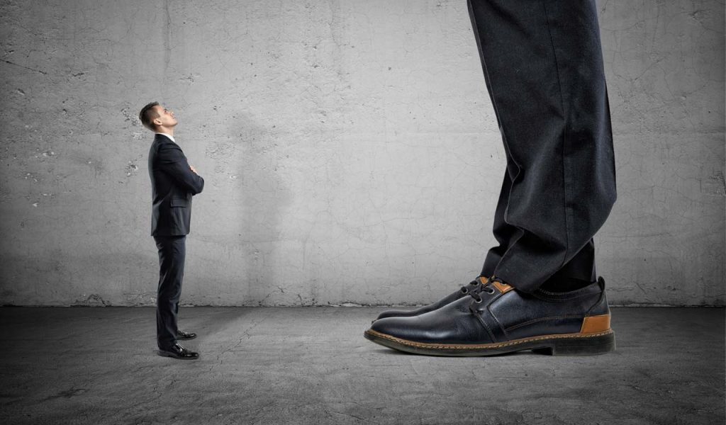 a tiny businessman standing in front of a giant business man