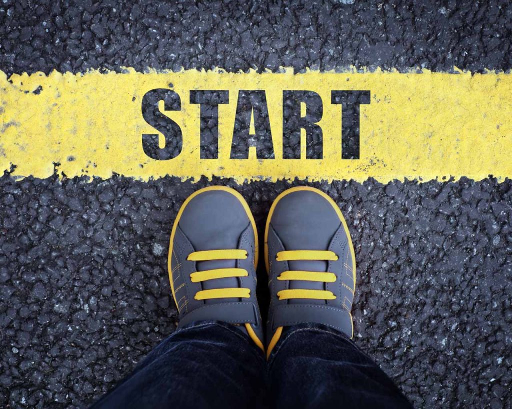 Feet standing at a starting line painted on road