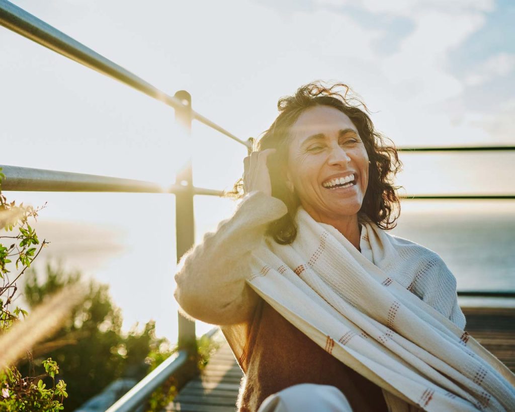 Happy woman sitting on a lakeside deck